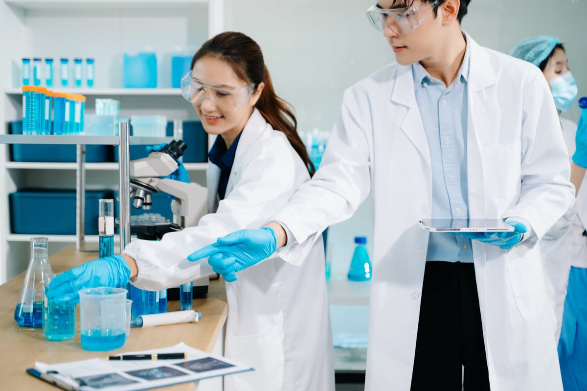Scientists conducting research investigations in a medical laboratory, a researcher using a microscope — D-2-4 visa guide featured image